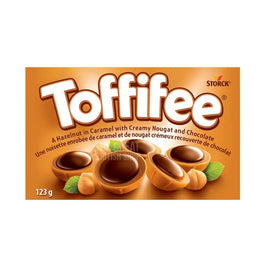 Toffifee 123g, front of pack showing hazelnuts in caramel, chocolate and leaves.